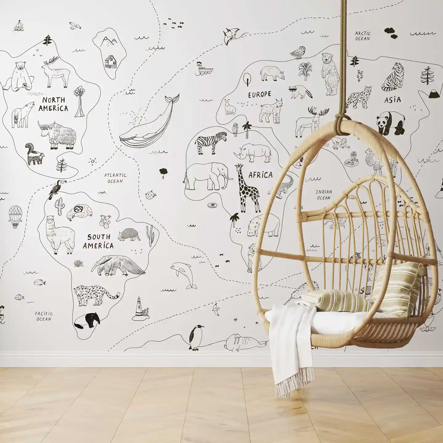 Tapete Weltkarte minimalistisch in Schwarz-Weiß, davor ein Hängesessel aus Rattan mit Kissen und Decke