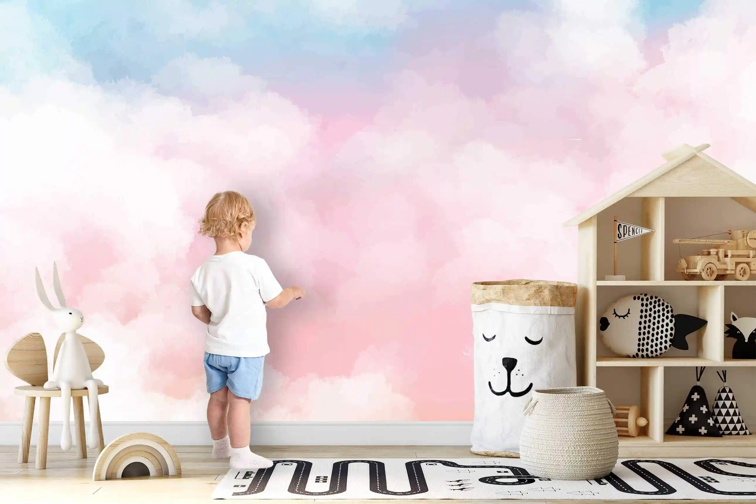 Pastell Wolken Tapete im Kinderzimmer, Kleinkind berührt die Wand neben Hausregal und Aufbewahrungssack mit Bärengesicht