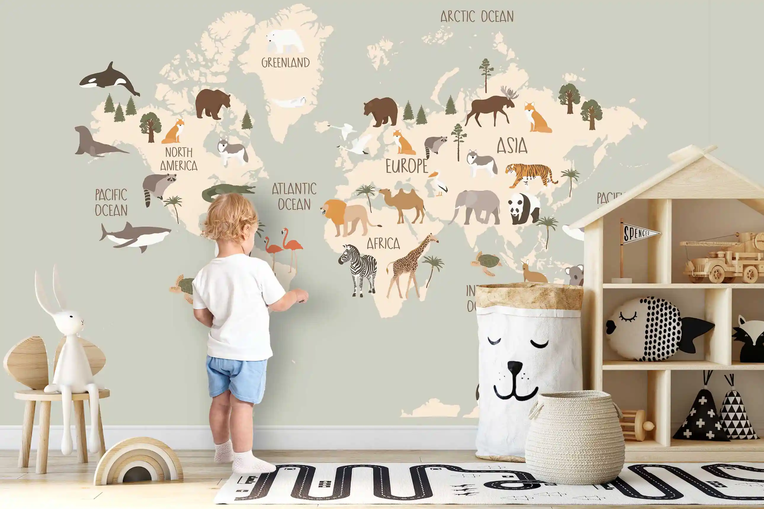 Boho Tier Weltkarte Tapete in Beige und Salbei, Kleinkind berührt die Karte neben einem Hausregal mit Spielzeug